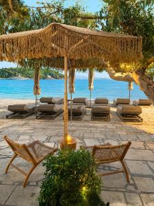 Ein Strohschirm und Stühle an einem Strand mit dem Meer in der Unterkunft Eva Beach Hotel Lefkada in Nydri