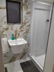 a bathroom with a sink and a shower with a television at Ultimate Grace in Pretoria