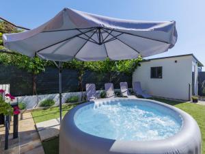 a pool with an umbrella and chairs in a yard at Apartment L&V by Interhome in Galižana