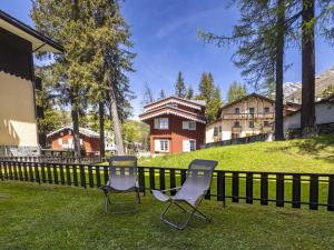 two chairs sitting in the grass in front of a fence at Apartment Villa Adele by Interhome in Madesimo
