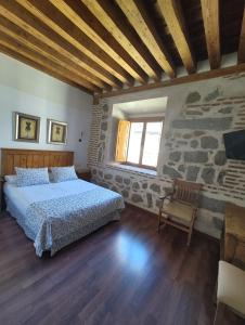 ein Schlafzimmer mit einem Bett und einer Steinwand in der Unterkunft HOTEL EL RASTRO - Palacio Duque de Tamames - in Avila