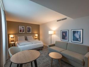 a hotel room with a bed and a couch and a table at Mercure Parkhotel Mönchengladbach in Mönchengladbach