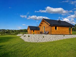 a log cabin in a field with a stone wall at Podhalańskie Chaty in Rokiciny Podhalanskie