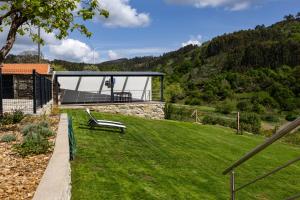 a garden with a bench in the grass at Casa Da Eira Caramulo in Varzielas