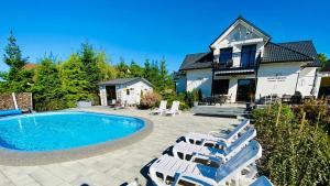a house with a swimming pool and some lounge chairs at Apartamenty Różany Ogród in Łeba