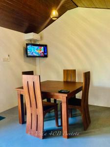 a dining room table and chairs with a television on the wall at Villa 40B Bentota in Bentota