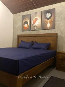 a bedroom with a bed with blue sheets and pictures on the wall at Villa 40B Bentota in Bentota