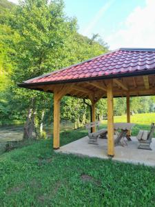 a wooden pavilion with a picnic table and benches at Apartman Džanan in Jajce