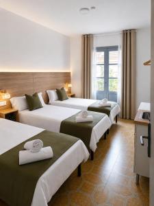 a hotel room with three beds with towels on them at Pensión Bandrés Huesca Centro in Huesca