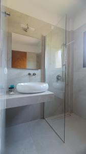 a bathroom with a sink and a tub and a mirror at Raptis Aparthotel Sivota in Syvota