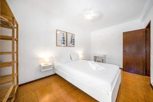 a white bed in a white room with two lamps at BeGuest Ferragudo Sunny Apartment in Ferragudo