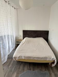 a bedroom with a bed with white sheets and a wooden floor at Appart Résidence Yadah RDC in Granville