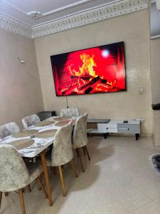 a dining room with a table and a fire on the wall at maison soleil in Nouaceur