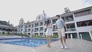a man and a woman walking by a swimming pool at Hotel Turístico de Tenza in Tenza