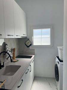 a white kitchen with a sink and a window at Piazza Apartments in Velipojë +52 photos