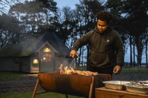 a man is cooking food on a grill at Scald Law Cabin in Kirknewton