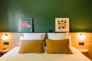 a bed with two pillows and a green wall at Sure Hotel by Best Western Tours Sud in Chambray-lès-Tours