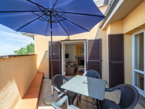 a table and chairs with a blue umbrella on a balcony at Apartment Villa Elisa by Interhome in Castellina in Chianti