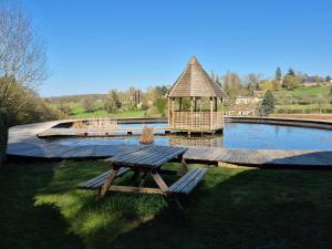 a wooden deck with a gazebo next to a pond at Yourte in Les Hogues