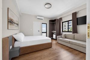a white bedroom with a bed and a couch at Casa Del Sol Seaside Hotel in Durrës