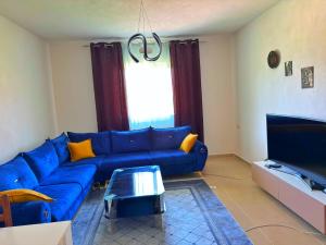a living room with a blue couch and a tv at Olive GREEN house in Durrës