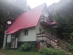 a small white house with a red roof at Bartók kulcsosház in Pietroasa