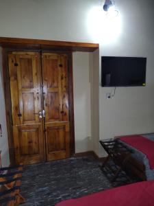 a room with a wooden door and a tv on the wall at Casa de Adobe Doña Tinogasta in Tinogasta