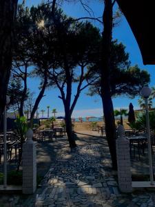 a walkway with tables and trees on the beach at Hotel Ylberi in Golem