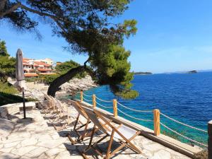 a row of chairs sitting next to the ocean at Seaside Apartments Sunny Prižba in Blato