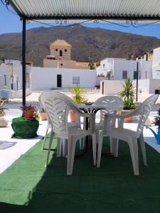 two white chairs and a table on a patio at La casita de la vito in Illar