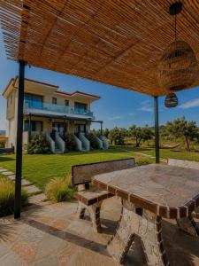 a picnic table under a wooden umbrella in front of a house at AENAON view in Ormos Panagias