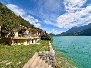 a house on the shore of a body of water at La cabane les pieds dans l'eau, accès direct au lac d'Annecy in Doussard