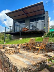 two chairs and a house with a balcony at Cabana Chácara Vilagio daspedras in Nova Petrópolis
