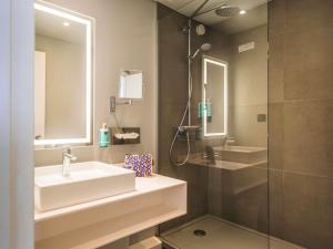 a bathroom with a sink and a shower at Novotel Caen Côte de Nacre in Caen