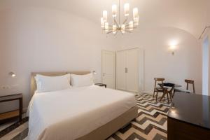 a bedroom with a white bed and a chandelier at Bambagina Mare in Amalfi
