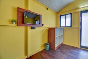 a room with yellow walls and a tv on the wall at Hotel Briko Lodging & Resort in Nashik