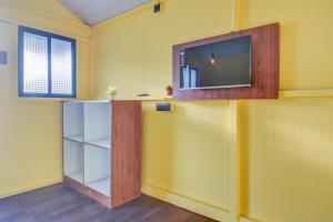 a room with a tv on a yellow wall at Hotel Briko Lodging & Resort in Nashik