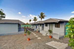 a row of cottages with palm trees in the background at Hotel Briko Lodging & Resort in Nashik