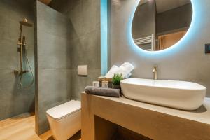 a bathroom with a sink and a toilet and a mirror at Grava Aurum - City Suites in Igoumenitsa