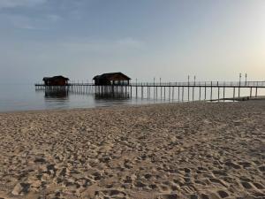 a sandy beach with a pier in the water at All Home in Cholpon-Ata