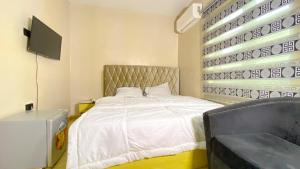 a bedroom with a white bed with a tv on the wall at H&Ts Bars and Hotels in Ibadan
