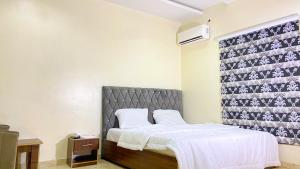 a bedroom with a bed and a wall at H&Ts Bars and Hotels in Ibadan