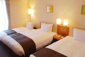 a hotel room with two beds and a phone at Rembrandt Hotel Atsugi in Atsugi