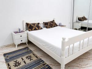 a white bed in a room with a mirror at Cozy Retreat in Bou Ficha