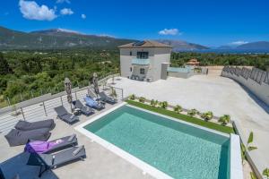 a swimming pool on a patio with chairs and a house at Agemaya Villas in Sami