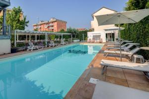 ein Schwimmbecken mit Stühlen und einem Sonnenschirm in der Unterkunft Jet Hotel, Sure Hotel Collection by Best Western in Gallarate