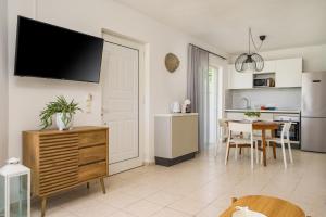 a kitchen and living room with a television on a wall at Einalia Holiday Homes by the Beach in Kardamaina