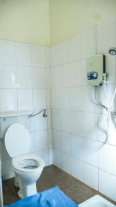 a bathroom with a toilet and a soap dispenser on the wall at SuPas Bistro in Kisoro
