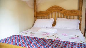 a bed with a wooden headboard and two pillows at SuPas Bistro in Kisoro