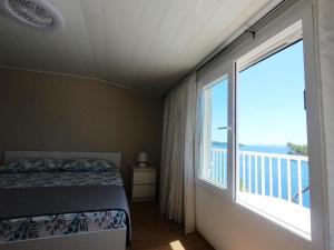 a bedroom with a bed and a large window at Seaside Apartments Sunny Prižba in Blato